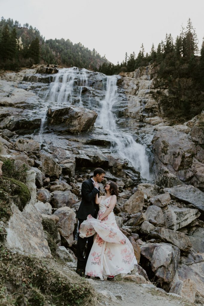 Couple looking at each other on their elopement day in front of grand waterfall 