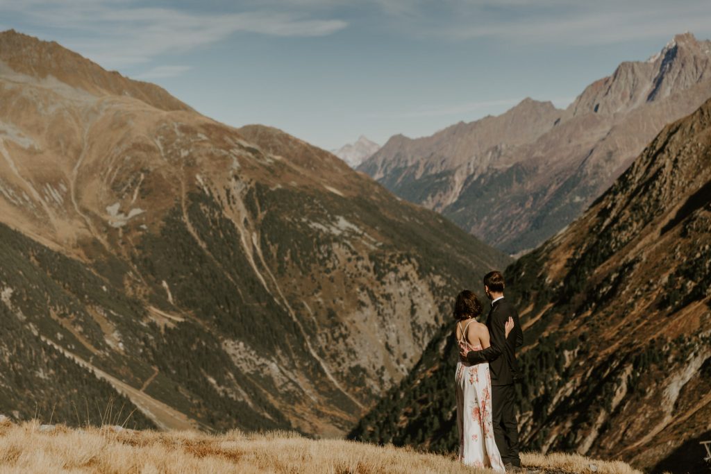 Bride and groom looking at epic mountainous backdrop on their wedding day in Austria